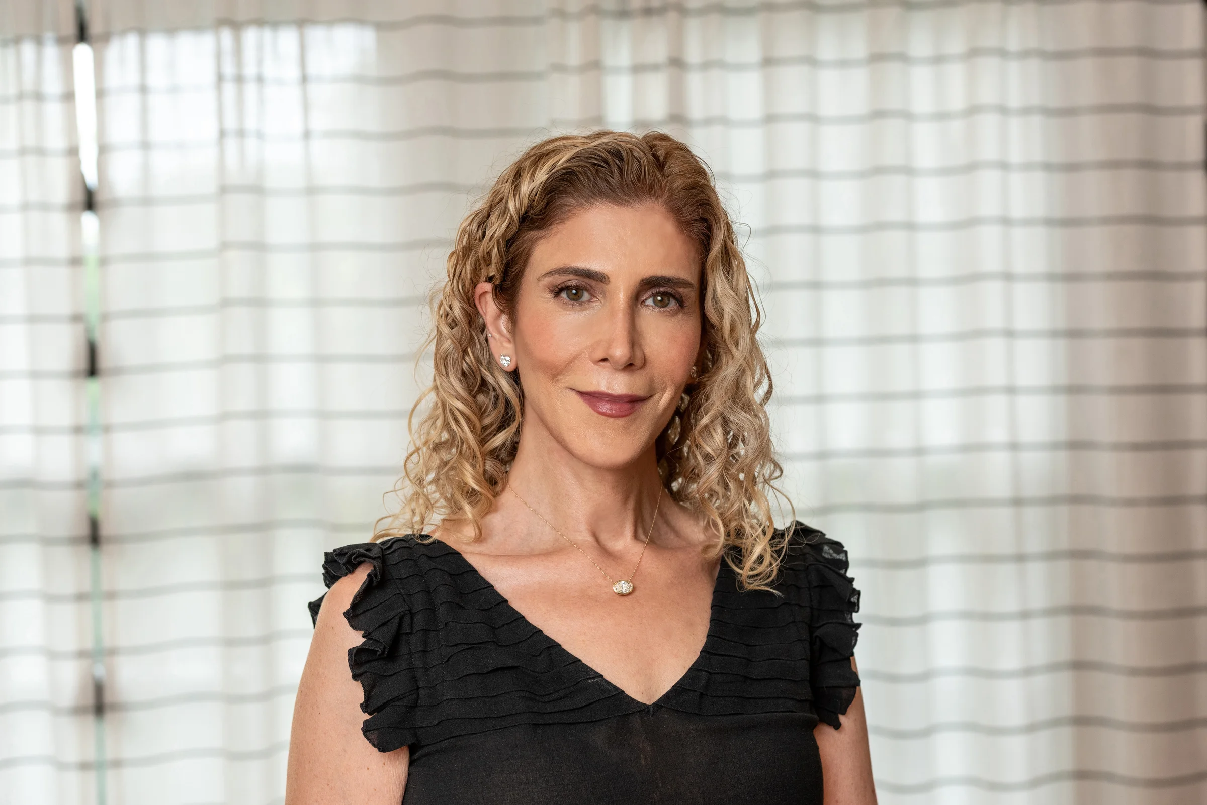Woman wearing diamond necklace and earrings, warm neutral styling